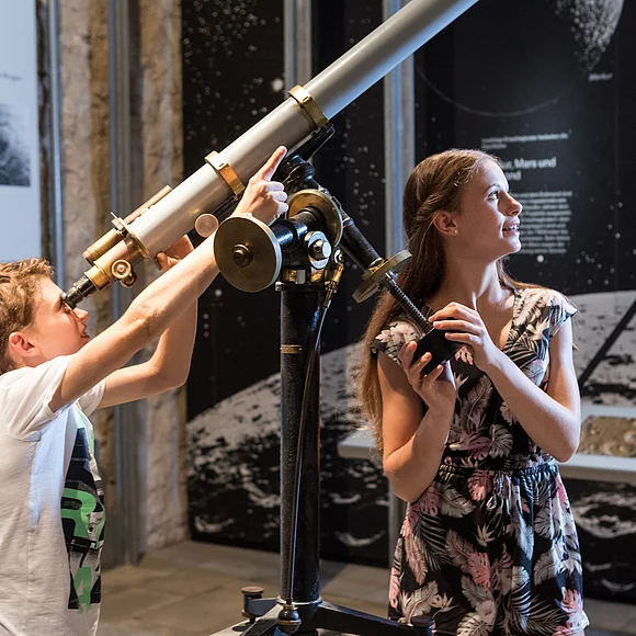 Zwei Kinder schauen durch ein Teleskop