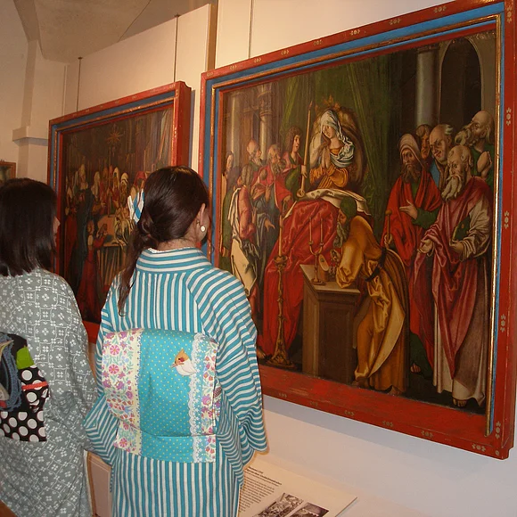 Zwei Frauen in asiatischer Kleidung sehen sich ein Gemälde an