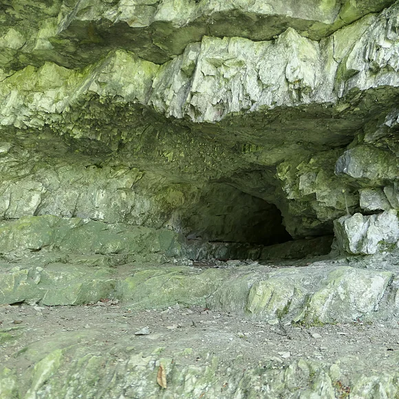 In einer Felswand aus geschichtetem Gestein befindet sich ein Loch.