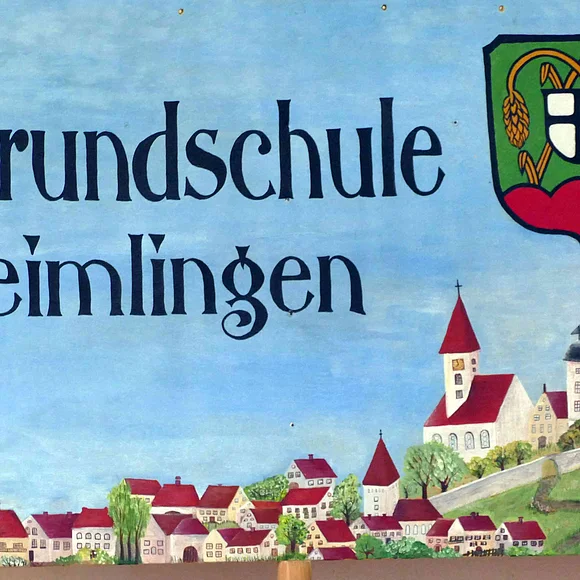 Das Schild der Grundschule Reimlingen zeigt den Namen der Schule, das Wappen der Gemeinde und eine Zeichnung einiger Gebäude der Gemeinde.