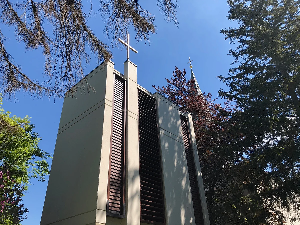 Außenansicht der Kirche Christi Himmelfahrt - gerader Turm ohne Spitze darauf ein großes Kreuz.