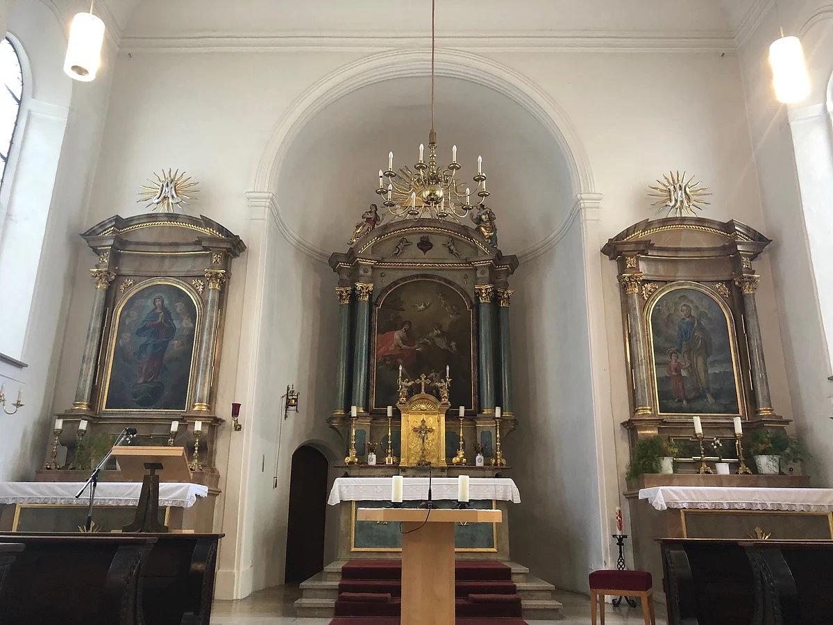 Blick auf den Innenraum der Spitalkirche, mit Hauptaltar und zwei Seitenaltaren.