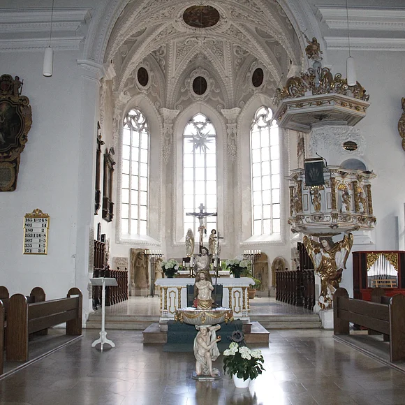 Blick in den hellen Innenraum auf den Altar mit rechts daneben liegender Kanzel.