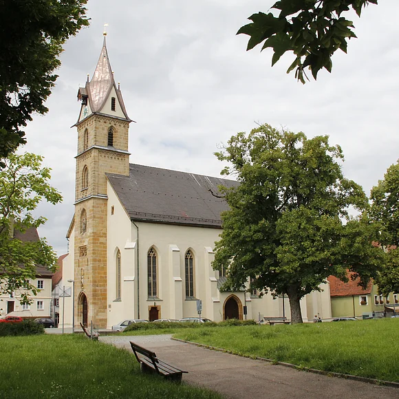 Blick auf die Pfarrkirche St. Sebastian, die teilweise hinter Bäumen verborgen ist.