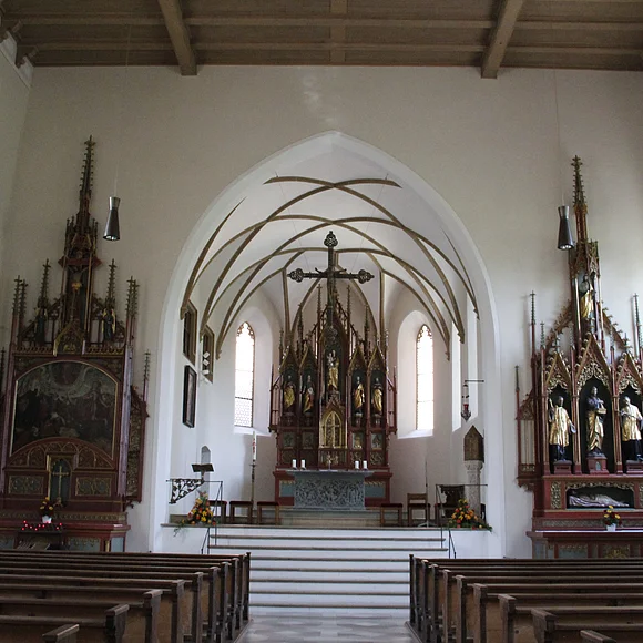 Blick auf das schlichte Innere von St. Sebastian. Vorne in der Mitte der Hauptaltar. Rechts und links im Bild die beiden Seitenaltäre sowie ganz vorne links im Bild die Kanzel.