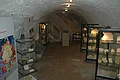 In einem Gewölbekeller stehen mehrere Vitrinen mit Gesteinsexponaten. An der Wand stehen zwei große Informationstafeln.