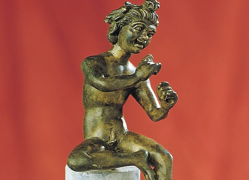 Suonatore di flauto romano proveniente da Holheim Auf einem kleinen Stab sitzt eine Bronzefigur, die die Hände wie zum Flötenspiel hält.