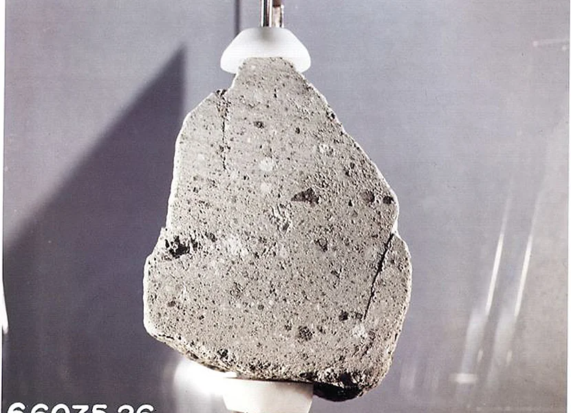 Pietra lunare della missione Apollo 16 esposta nel Rieskratermuseum di Nördlingen Auf einem Träger befindet sich ein graues Gesteinsstück mit hellen und dunklen Einschlüssen.