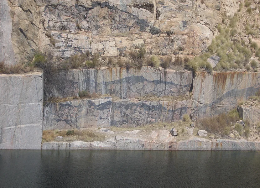 La cava di Leeukop Hügel (impattiti) nel cratere di Vredefort, in Sudafrica, età: 2,02 miliardi di anni Unterhalb der stufigen Wand eines Steinbruchs befindet sich ein See.