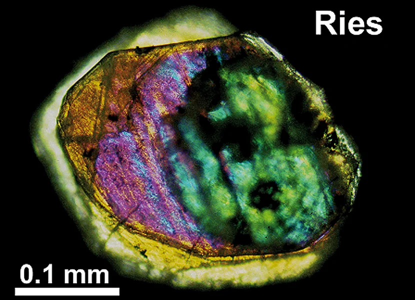Im Dünnschliff schimmert ein etwa 0.3 mm großer Riesdiamat orange, lila und grün.