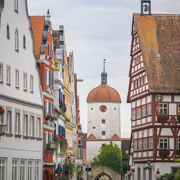Stadt Oettingen Straße mit historischen Gebäuden und einem Turm mit Uhr in der Mitte, umgeben von Fachwerkhäusern.