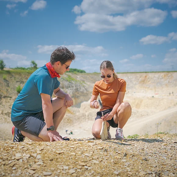 Fossilien suchen im Steinbruch Blumenberg Zwei Personen knien auf einem steinigen Gelände und untersuchen den Boden.