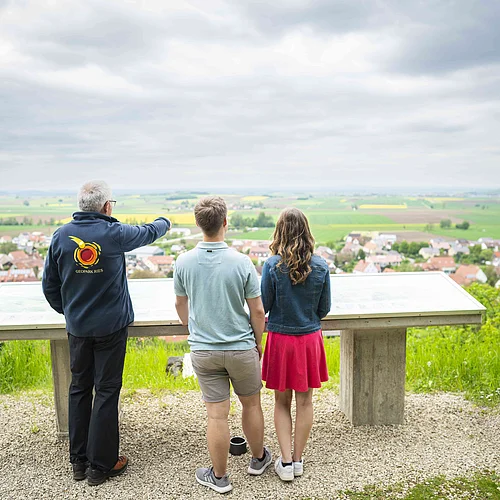 Geopark Ries Mai 2023 Ein Geopark Ries Führer zeigt einem Pärchen den Blick in den Rieskrater.